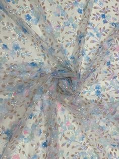 the fabric has flowers on it and is white with blue, pink and green colors