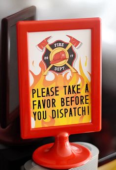 a fire department sign sitting on top of a red stand next to a microwave oven