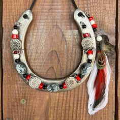 a metal horseshoe with beads and feathers hanging on a wooden wall