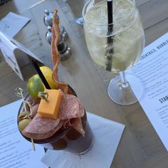 a drink with cheese, meat and fruit in it on a table at a restaurant