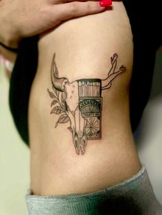 a woman with a tattoo on her stomach holding onto the side of her body, showing an image of a cow's head