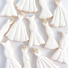 decorated cookies in the shape of wedding gowns and dresses are arranged on a white surface