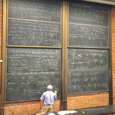 a man standing in front of a blackboard with lots of calculations written on it