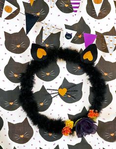 a wreath made out of black cats with purple and orange flowers on it, surrounded by halloween decorations