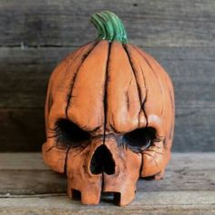 a carved pumpkin shaped like a skull sitting on top of a wooden table