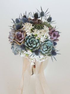 a bouquet of succulents and other flowers in a vase