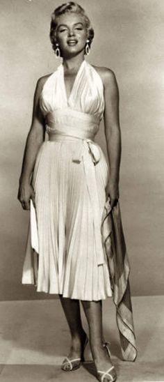 a black and white photo of a woman in a dress with her hands on her hips