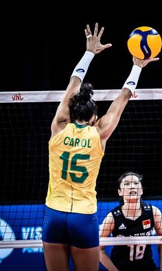 two women are playing volleyball and one is reaching up to hit the ball with her racket