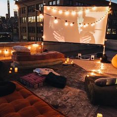 an outdoor movie is set up on the roof of a building with lights strung over it