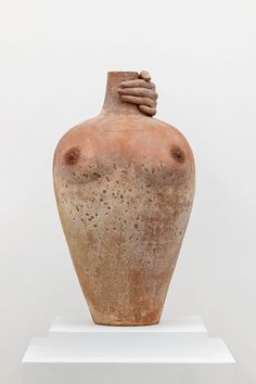 an old clay vase sitting on top of a white pedestal