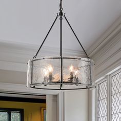 a chandelier hanging from the ceiling in a room with white walls and windows