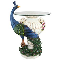 a peacock figurine sitting on top of a white vase next to a glass table