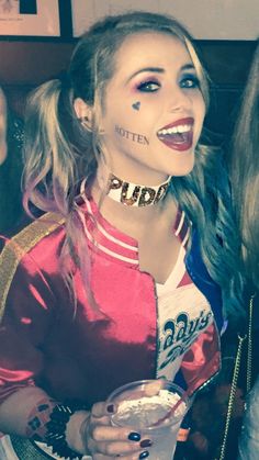 two girls with face paint and piercings on their faces, one holding a drink in her hand