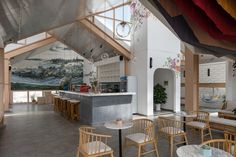 the inside of a restaurant with tables, chairs and paintings on the wall behind it