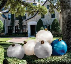 some white and blue ornaments are in front of a large house on the grass near a tree