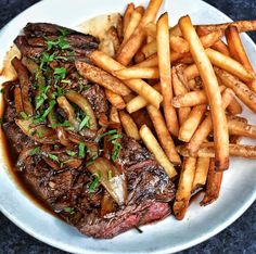 a steak and french fries on a white plate