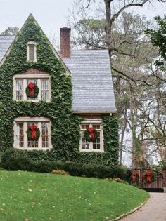 a house covered in ivy with wreaths and bows on it's front windows