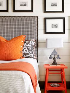 an orange and white bedroom with pictures on the wall above the bed, side table