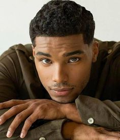 a close up of a person leaning on a table with his hand on his chest