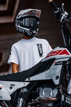 a person wearing a helmet and standing next to a dirt bike