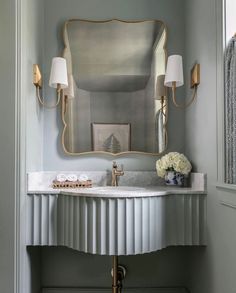 a white sink sitting under a mirror in a bathroom next to a wall mounted faucet