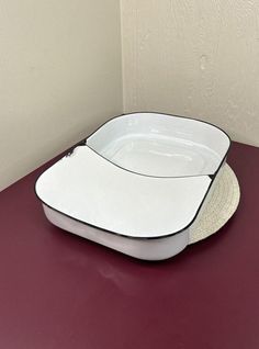 a white and black square dish sitting on top of a red counter next to a wall