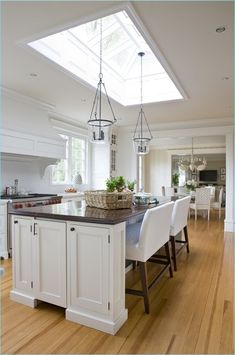 a large kitchen with white cabinets and an island in the middle, along with hardwood flooring