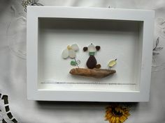 two birds sitting on a piece of wood with flowers in the background and a white frame