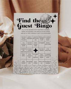 a sign that says find the guest bingo on it next to some flowers and tissue paper