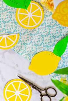 cut out lemons sitting on top of a table next to scissors and paper flowers