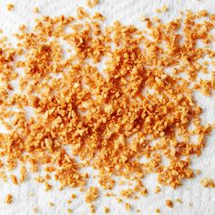 a pile of orange crumbs on top of a white surface with one piece missing