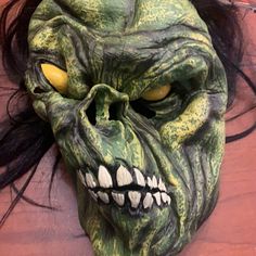 a green mask with yellow eyes and long hair