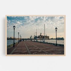 an empty pier with street lamps and water in the background