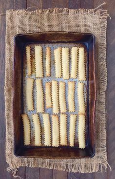 homemade macaroni and cheese squares in a baking pan on a wooden table top