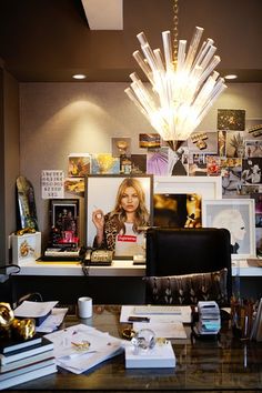 a desk with many items on it and a chandelier hanging from the ceiling