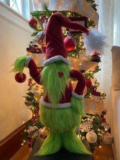 a large green and red christmas decoration in front of a tree