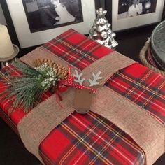 a wrapped present sitting on top of a table next to two pictures and a pine cone