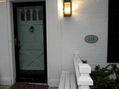 a white brick house with a black front door and light on the side walk way