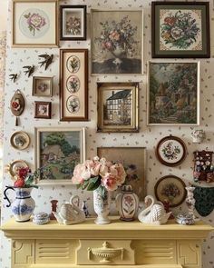 there are many pictures on the wall and vases in front of the fireplace mantel