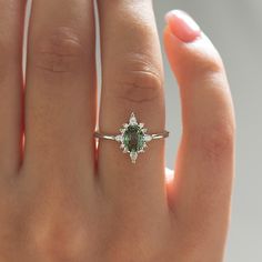 a woman's hand with a ring on it and a green stone in the middle