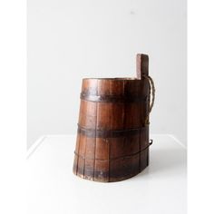 an old wooden bucket sitting on top of a white table next to a bottle opener