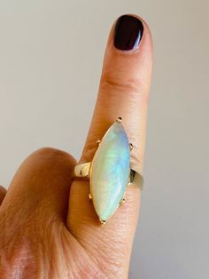 When you gaze into this stone, it feels as if you've been drawn into a little galaxy. A galaxy that is mesmerizing, mystical, and magical! You may even loose track of time while peering into this lovely gift from the earth. -The center stone is a marquise cut natural opal measuring 30mm X 10mm X 7.5mm.  -The shank is 14k yellow gold. -The total weight of the ring is 9.6 grams. -Ring Size 9.25.  Seller is a GIA Graduate Gemologist. Celestial Oval Cabochon Moonstone Ring, Celestial 14k Gold Opal Gemstone Ring, Unique Round Opal Ring For Healing, Spiritual Opal Birthstone Ring, Collectible Oval Cabochon Moonstone Ring, Celestial Oval Opal Birthstone Ring, Celestial Opal Birthstone Ring In Oval Shape, Spiritual Opal Ring For Healing, Mystical Oval Cabochon Rings