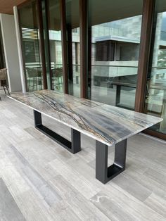 a marble table sitting on top of a hard wood floor next to a building with glass doors