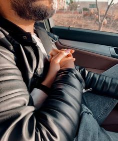 a man sitting in the back seat of a car with his hands on his lap