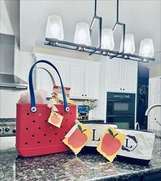 a red purse sitting on top of a kitchen counter next to an apple shaped bag