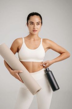 a woman holding a yoga mat and water bottle