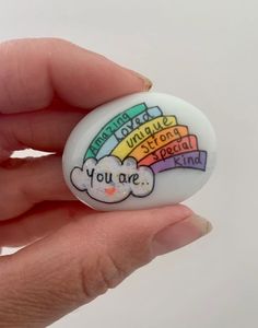 a hand holding a button with the words you are special kind in rainbows on it