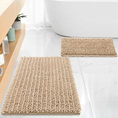 two bathroom rugs on the floor in front of a bathtub and countertop