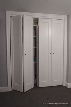 an empty closet with two doors open in a room that has carpeted flooring and gray walls