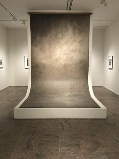 an empty room with several framed pictures on the wall and concrete flooring in front of it